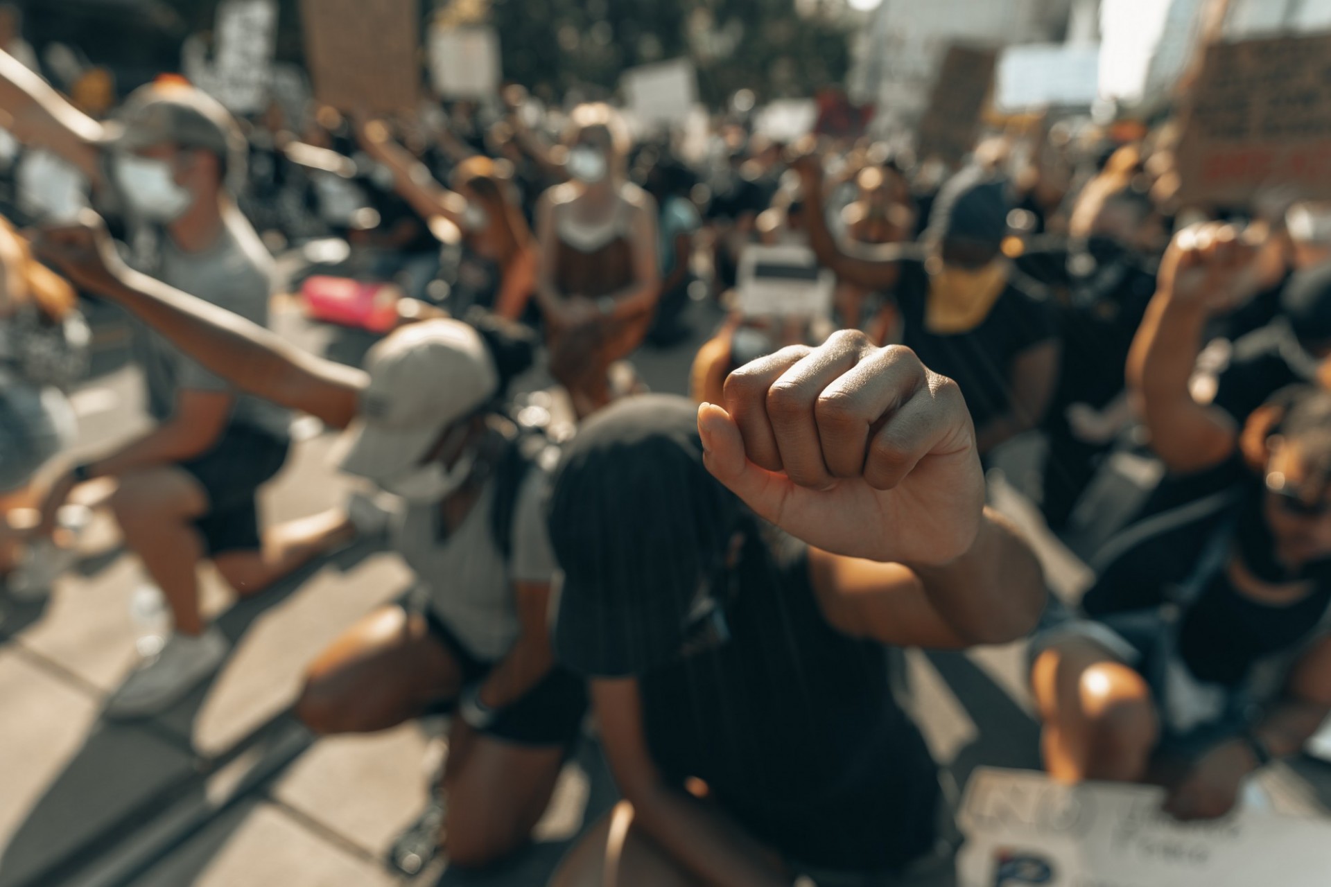 diverse people wearing masks kneeling with their fists up